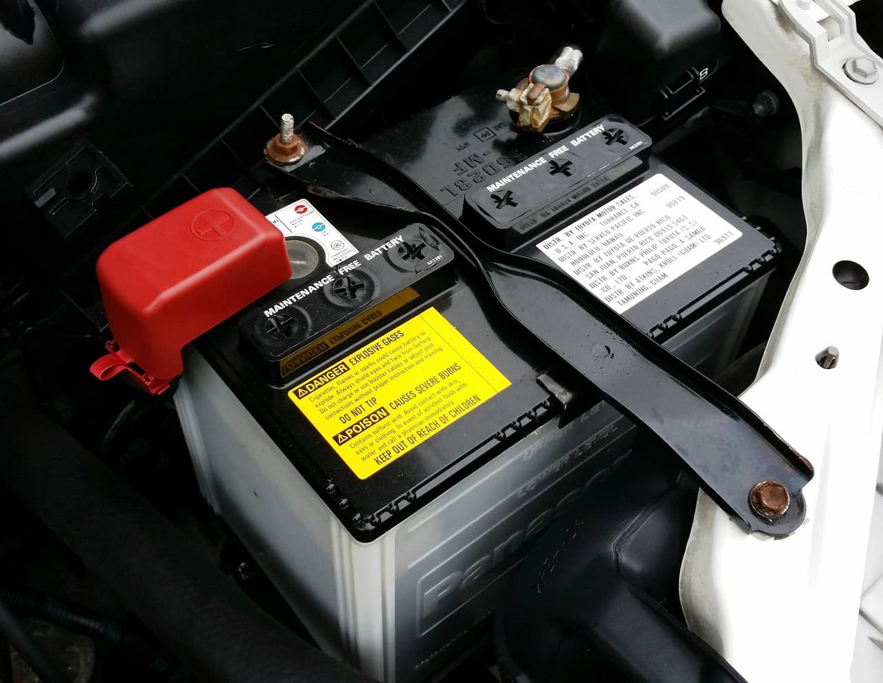 A car battery under the bonnet, red terminal cover on