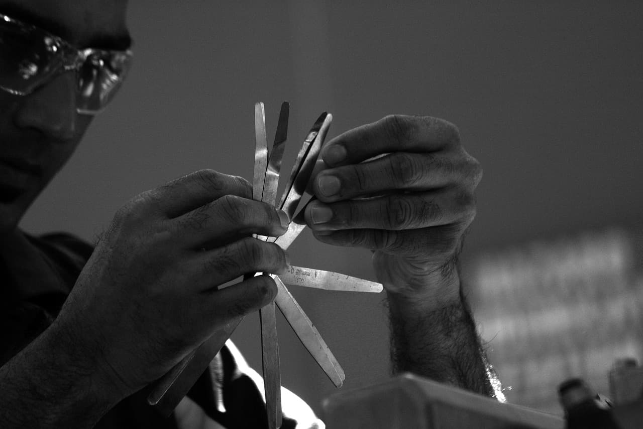 A mechanic's hands fanning out a set of feeler gauges